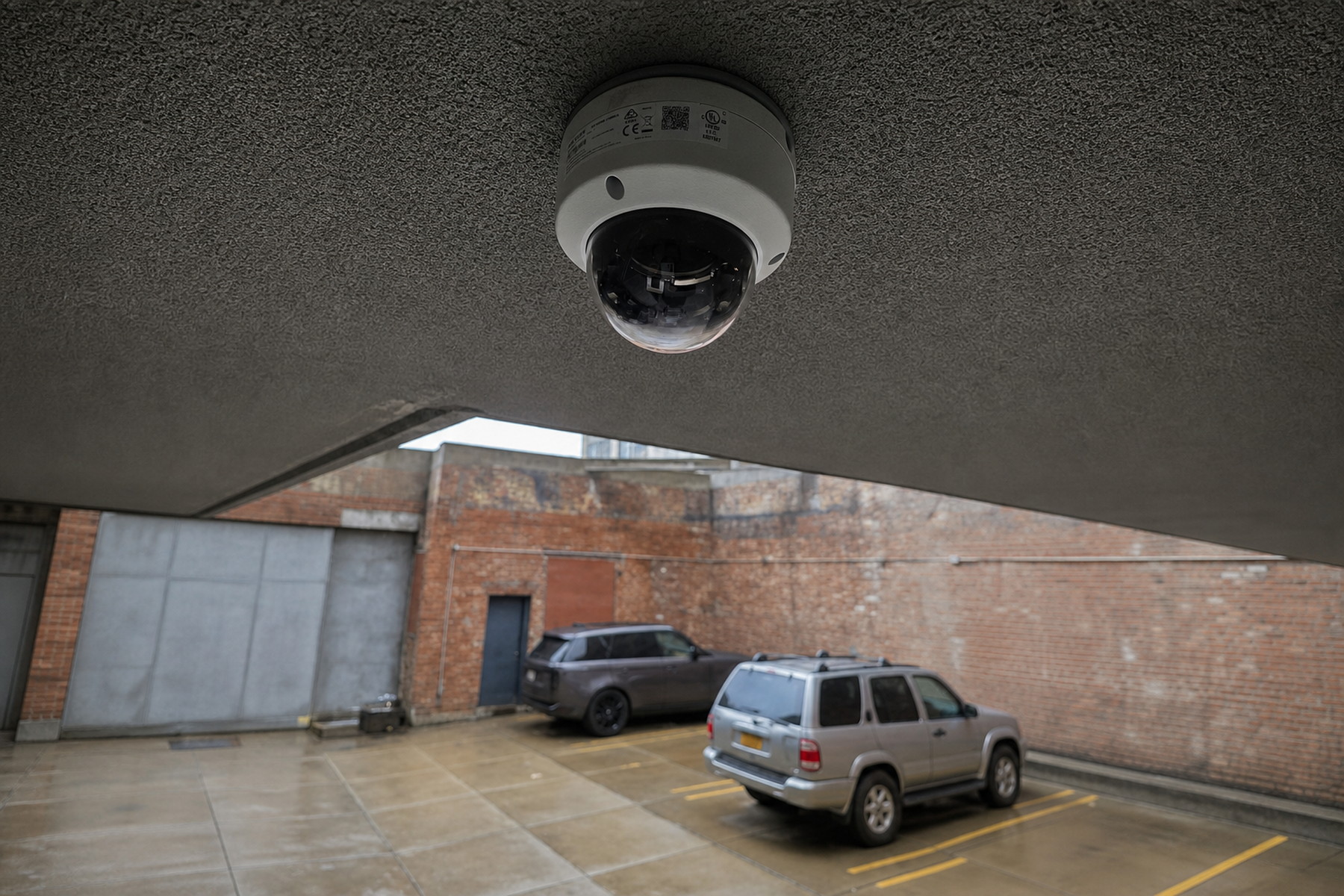 Ceiling-mounted dome security camera monitoring a covered parking area